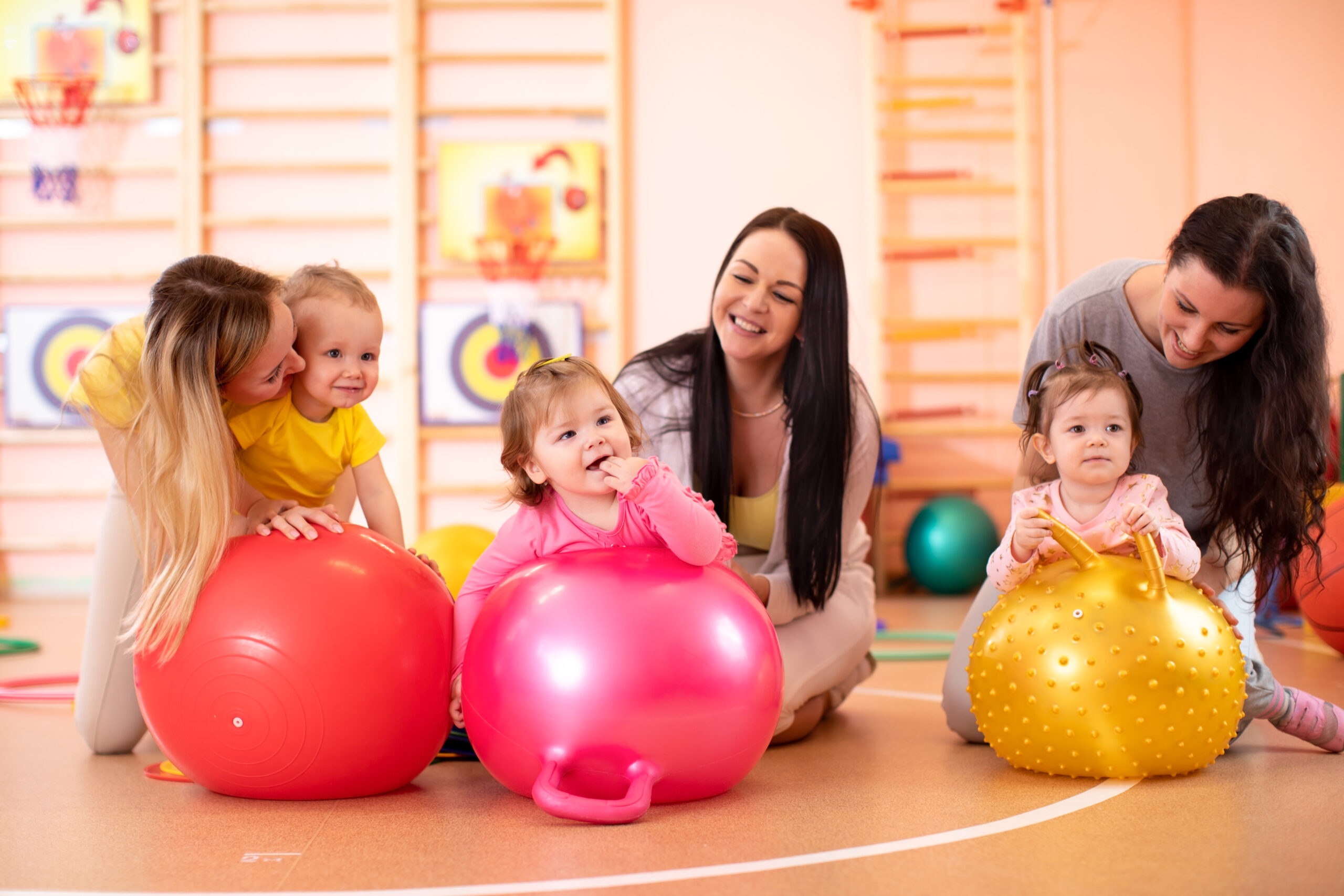 Mothers with happy babies doing exercises with gymnastic ball at fitness class. Concept of caring for the baby’s health.